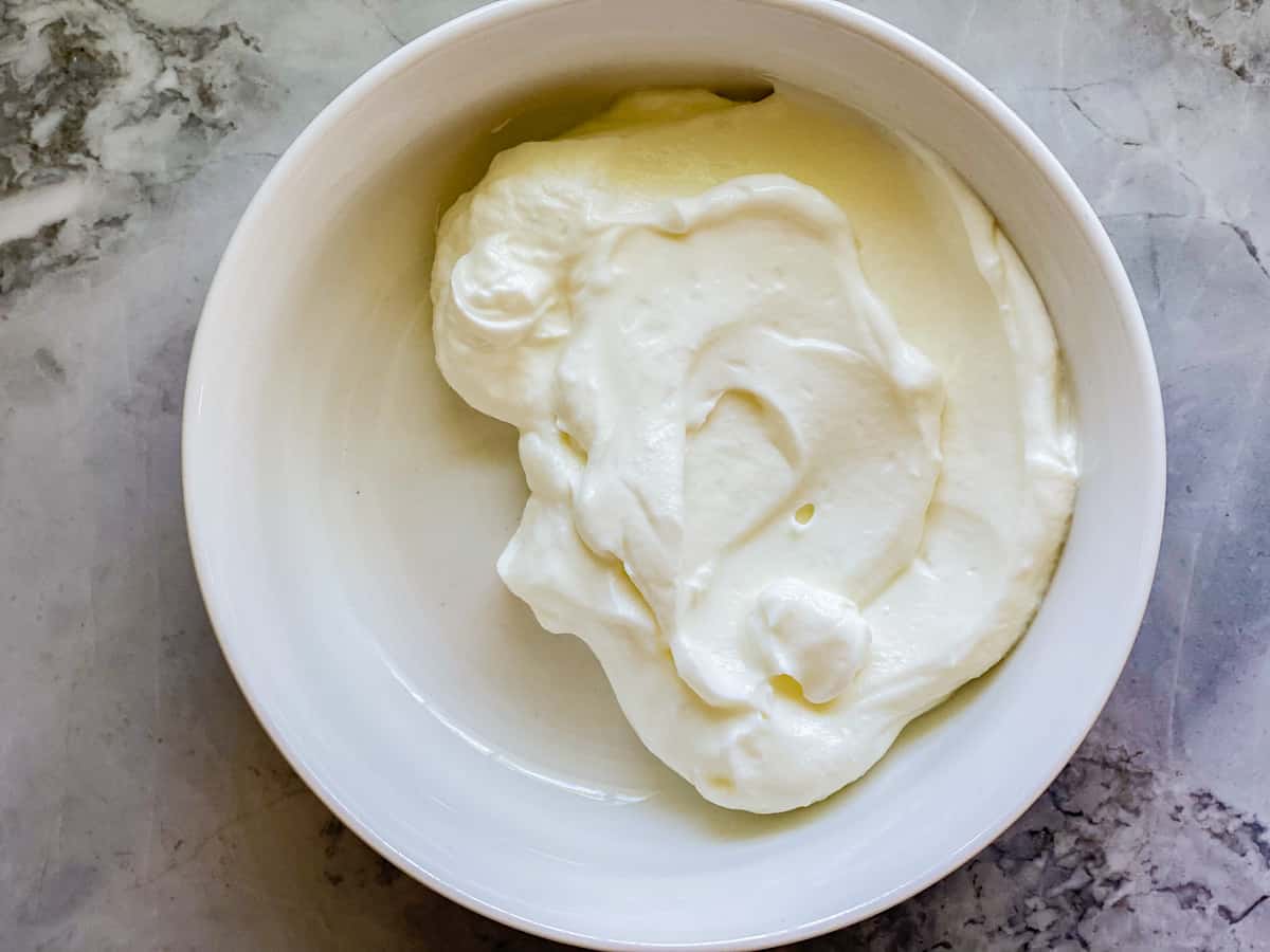 White bowl filled with half a bowl of white yogurt.
