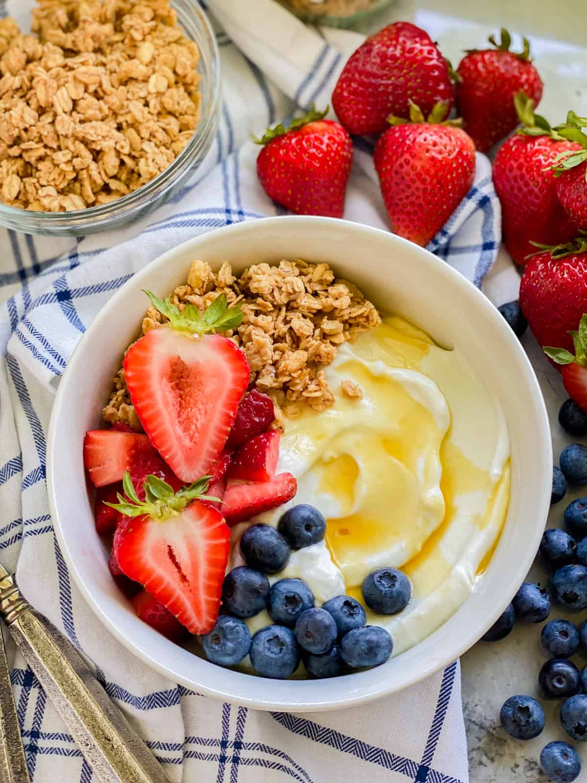 White bowl filled with yogurt, fruit and granola on a stripped napkin.
