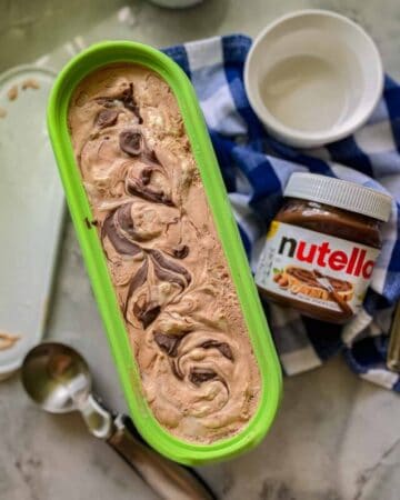 Green oval container with chocolate ice cream, ice cream scoop, and nutella container.