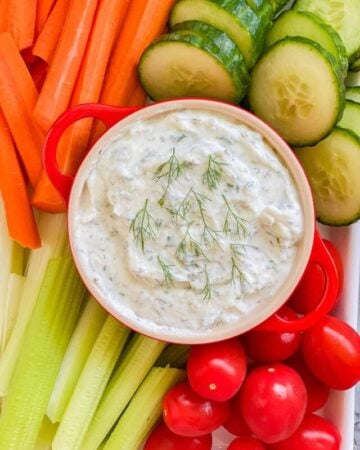 White dip with carrots, celery, cucumbers, and tomatoes.