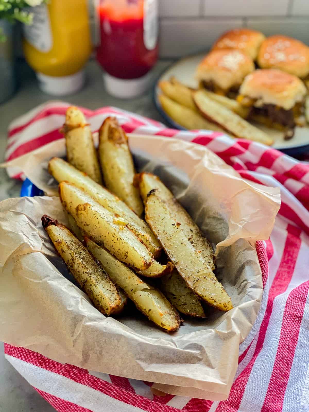 Blue basket lined with parchment and baked potato wedges.