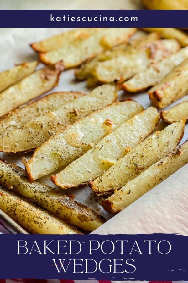 Parchment lined tray with baked potato wedges with recipe title text on image for Pinterest.