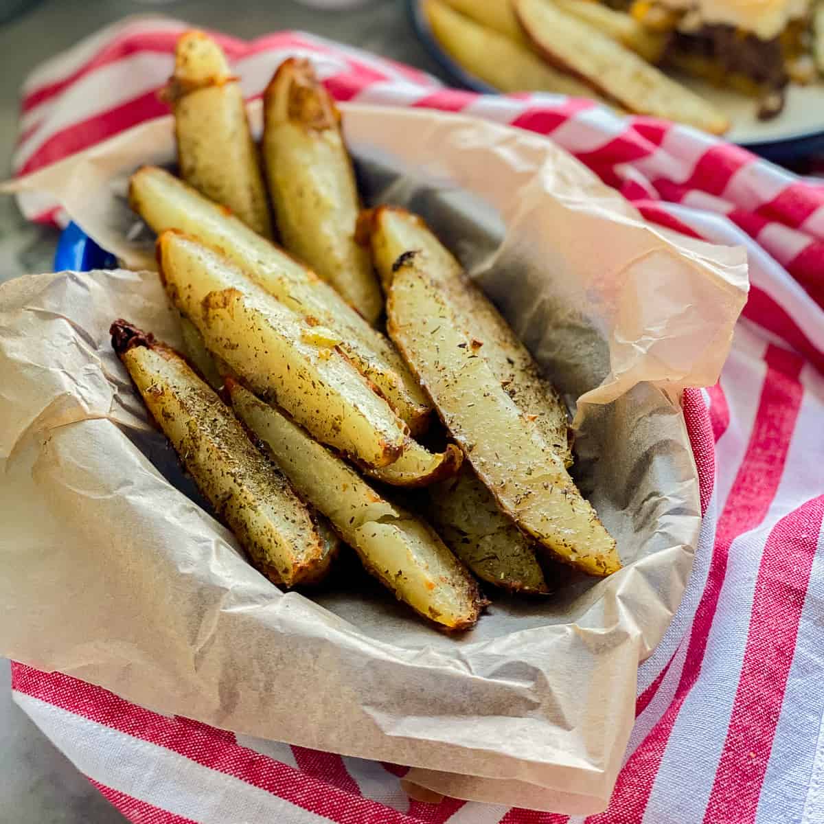 Basket filled with potato wedges on a red and white striped cloth.