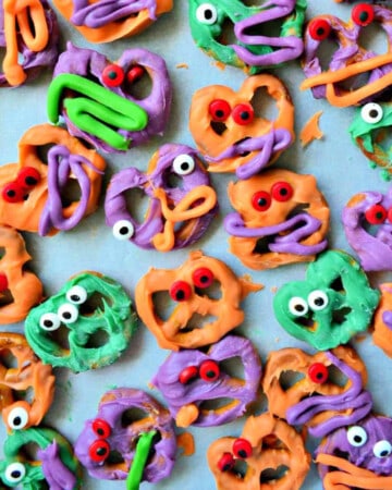 Pretzels dipped in colored white chocolate with eyeballs on the pretzels.