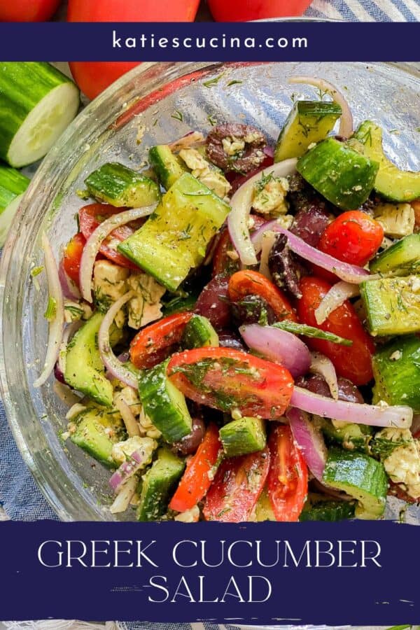 Glass bowl filled with cucumbers, tomatoes,s onions, olives, and feta with recipe title text on image for Pinterest.