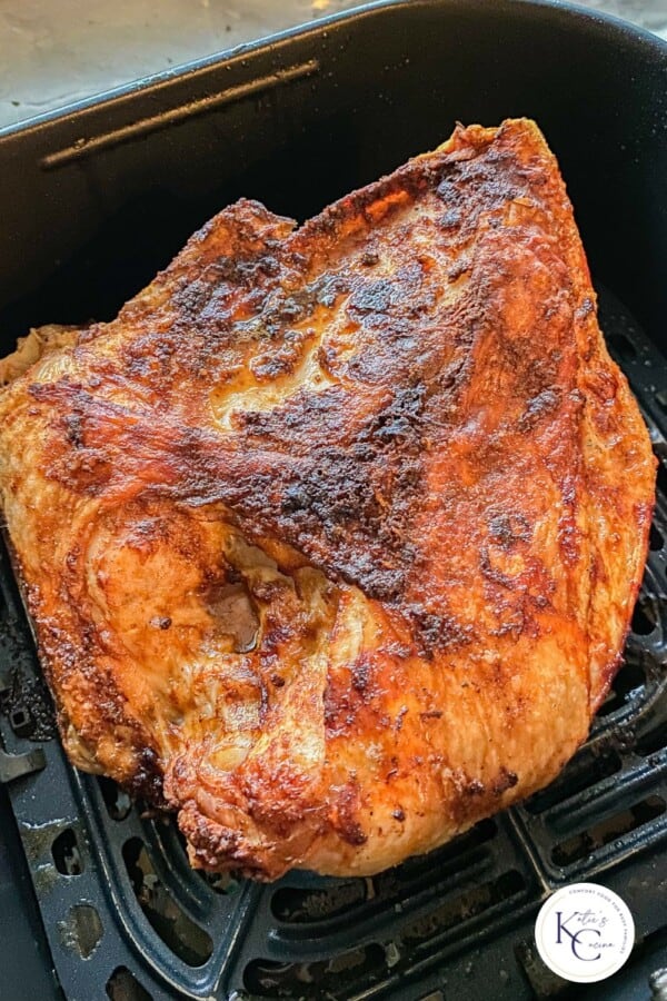 Golden cooked turkey breast in Air Fryer basket with logo on bottom right corner.