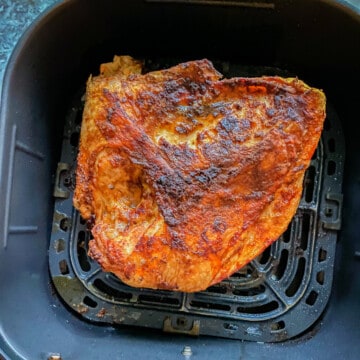 Cooked seasoned turkey breast in a black air fryer basket.