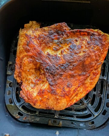 Cooked seasoned turkey breast in a black air fryer basket.