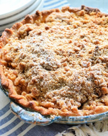 Glass plate filled with an apple pie with powdered sugar.