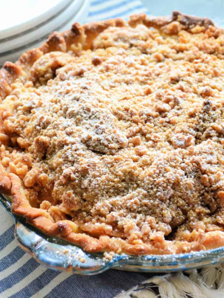 Glass plate filled with an apple pie with powdered sugar.