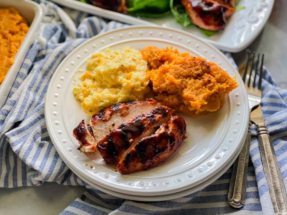 White plate filled with turkey, sweet potatoes, and corn casserole with fork next to plate.