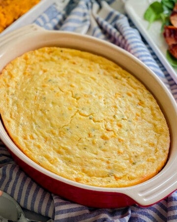 Oval red baking dish filled with corn casserole.