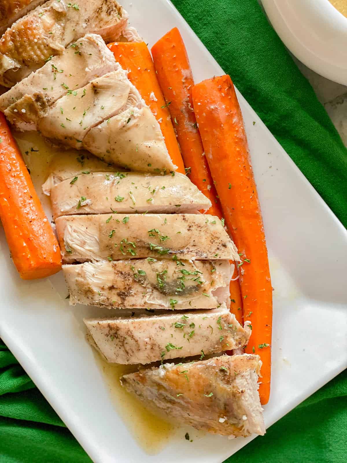 White plate filled with sliced turkey breast and carrots.