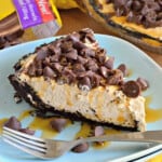 Blue plate filled with caramel pie with oreo crust and chocolate chips with fork on plate.