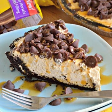 Blue plate filled with caramel pie with oreo crust and chocolate chips with fork on plate.