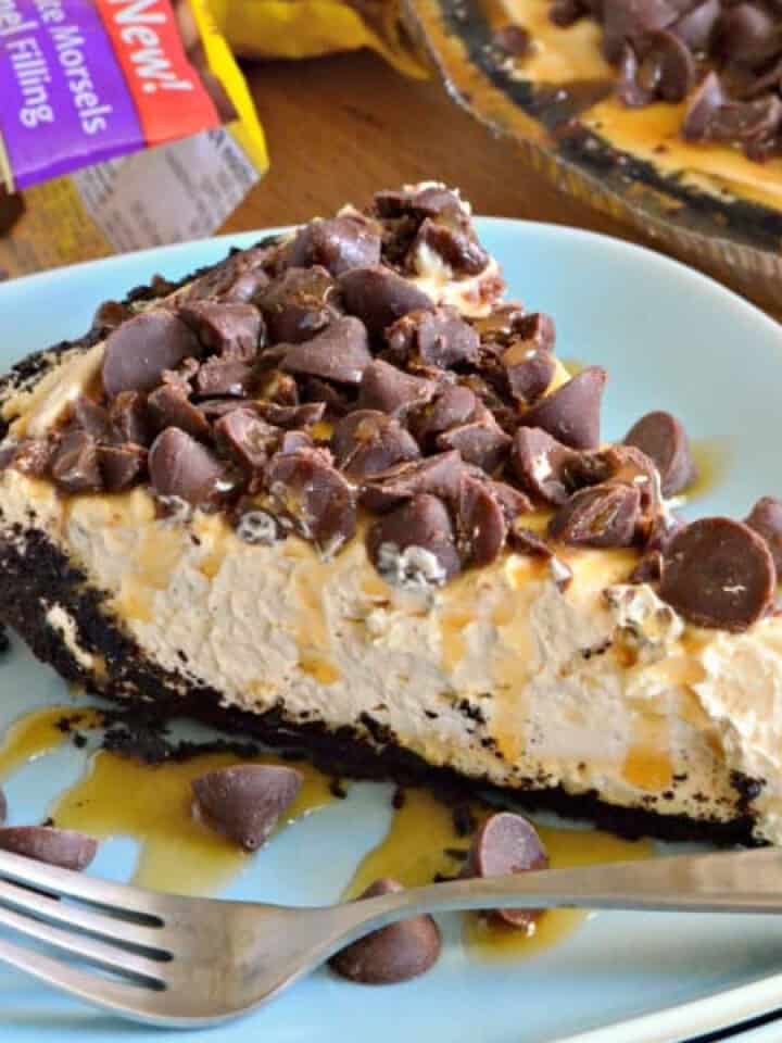 Blue plate filled with caramel pie with oreo crust and chocolate chips with fork on plate.