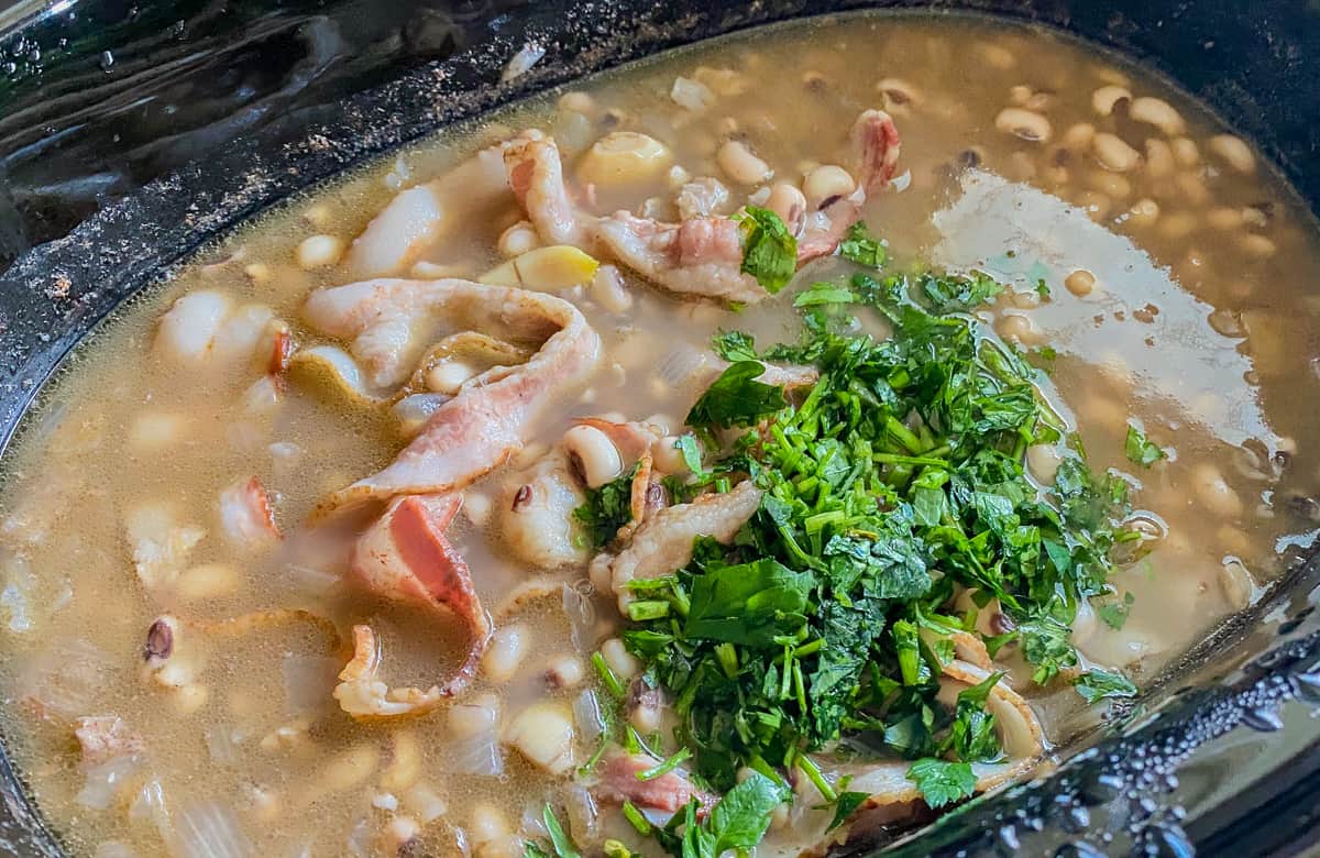 black oval dish with chopped parsley on top of cooked black eyed peas.