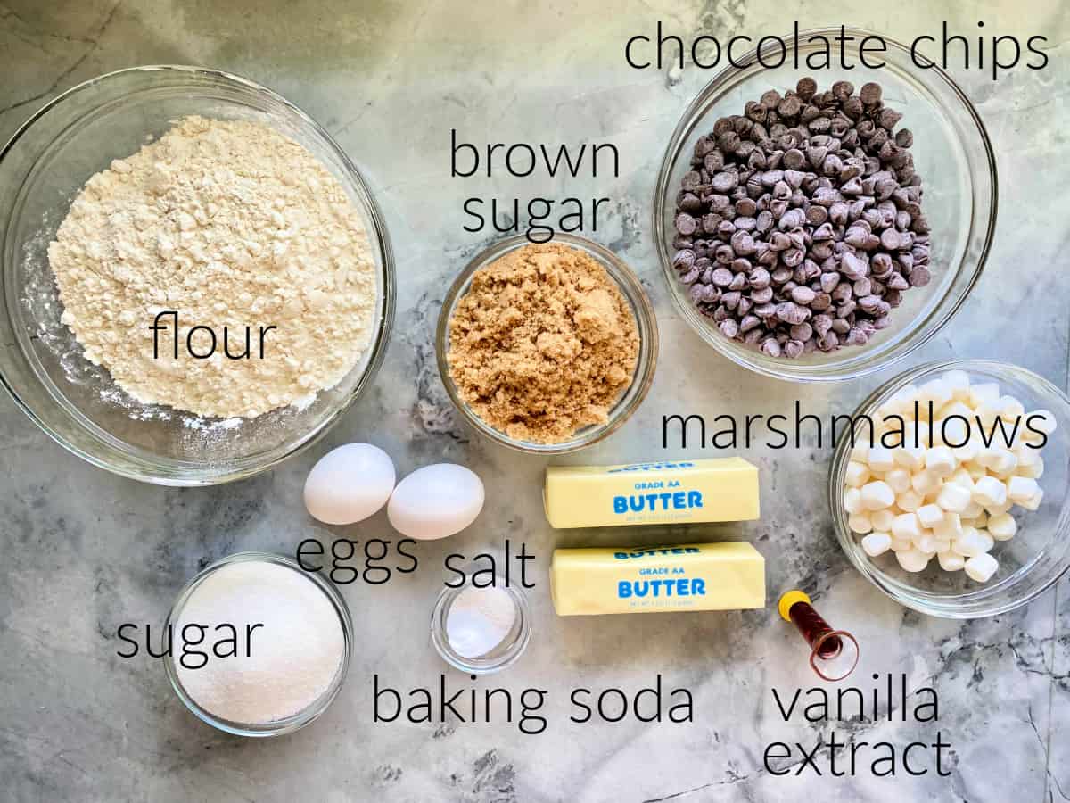 Ingredients on counter: flour, eggs, salt, sugar, baking soda, brown sugar, butter, chocolate chips, marshmallows, vanilla extract.