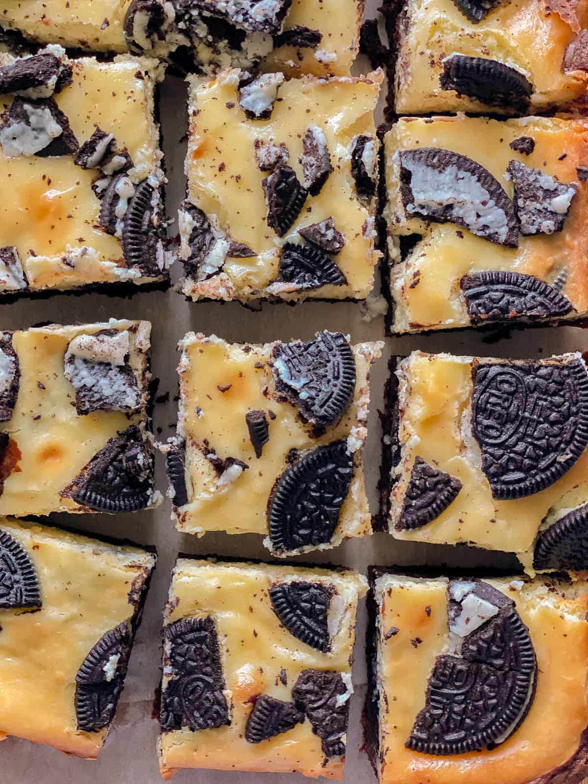 12 slices of cheesecake bars with Oreos crushed topped.