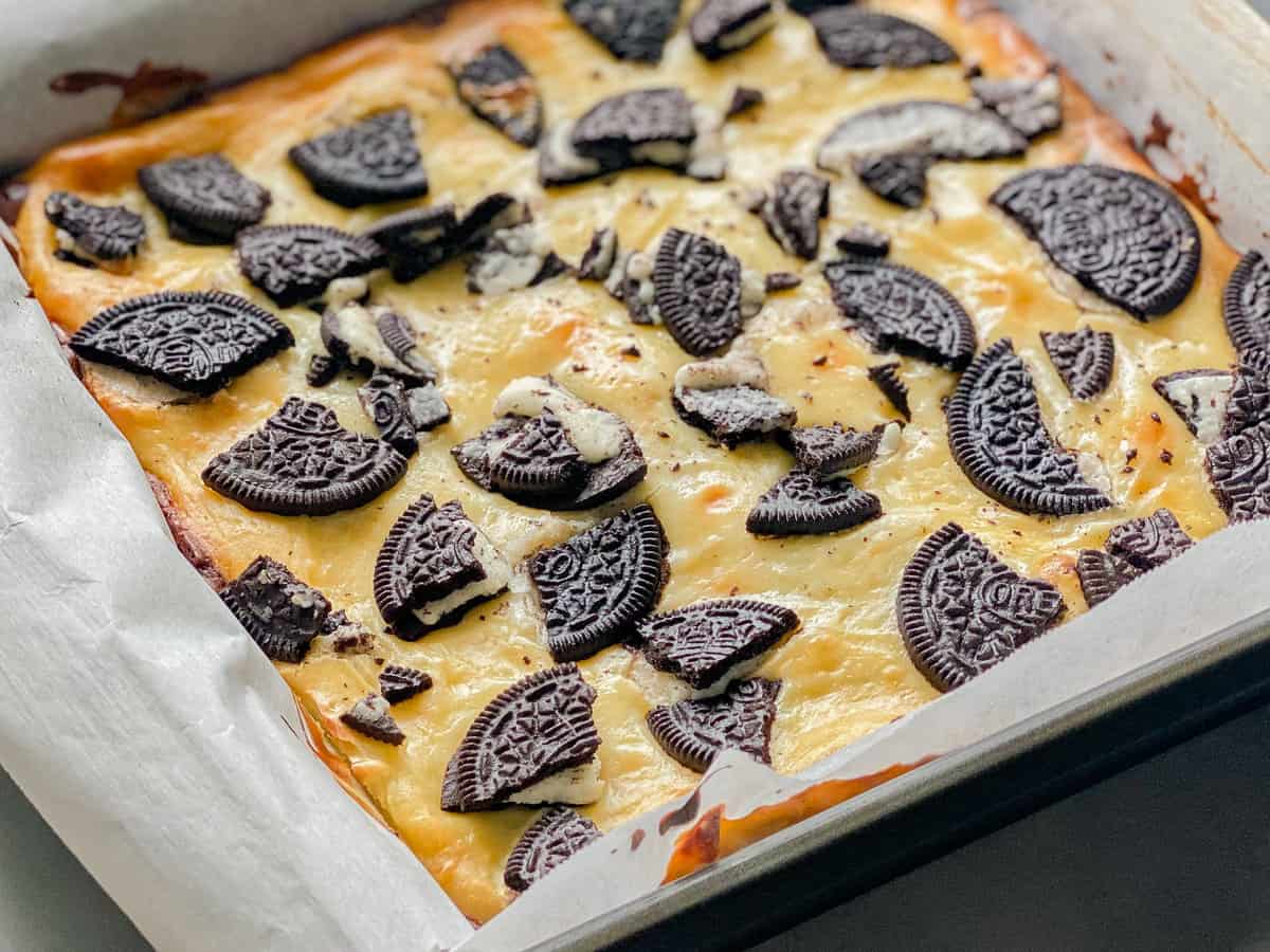 Square baking pan with baked Oreo's on cheesecake.