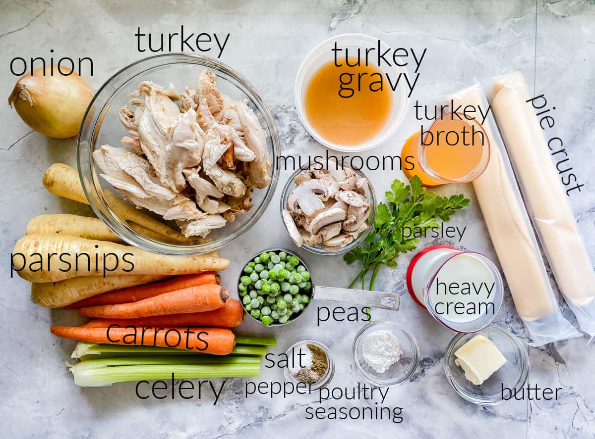 Ingredients on counter: turkey, onion, carrots, celery, parsnips, peas, mushrooms, parsley, heavy cream, pie crust, salt, pepper, pouldtry seasoning, corn starch, broth, gravy, and butter.
