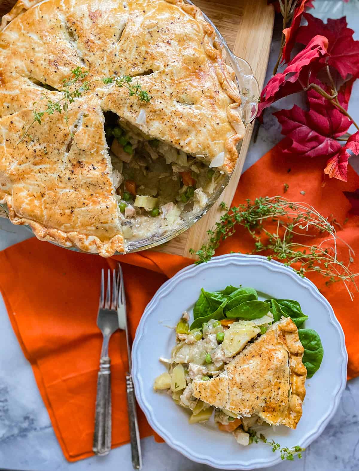 Turkey pot pie in a glass plate with a slice taken out on a white dish.