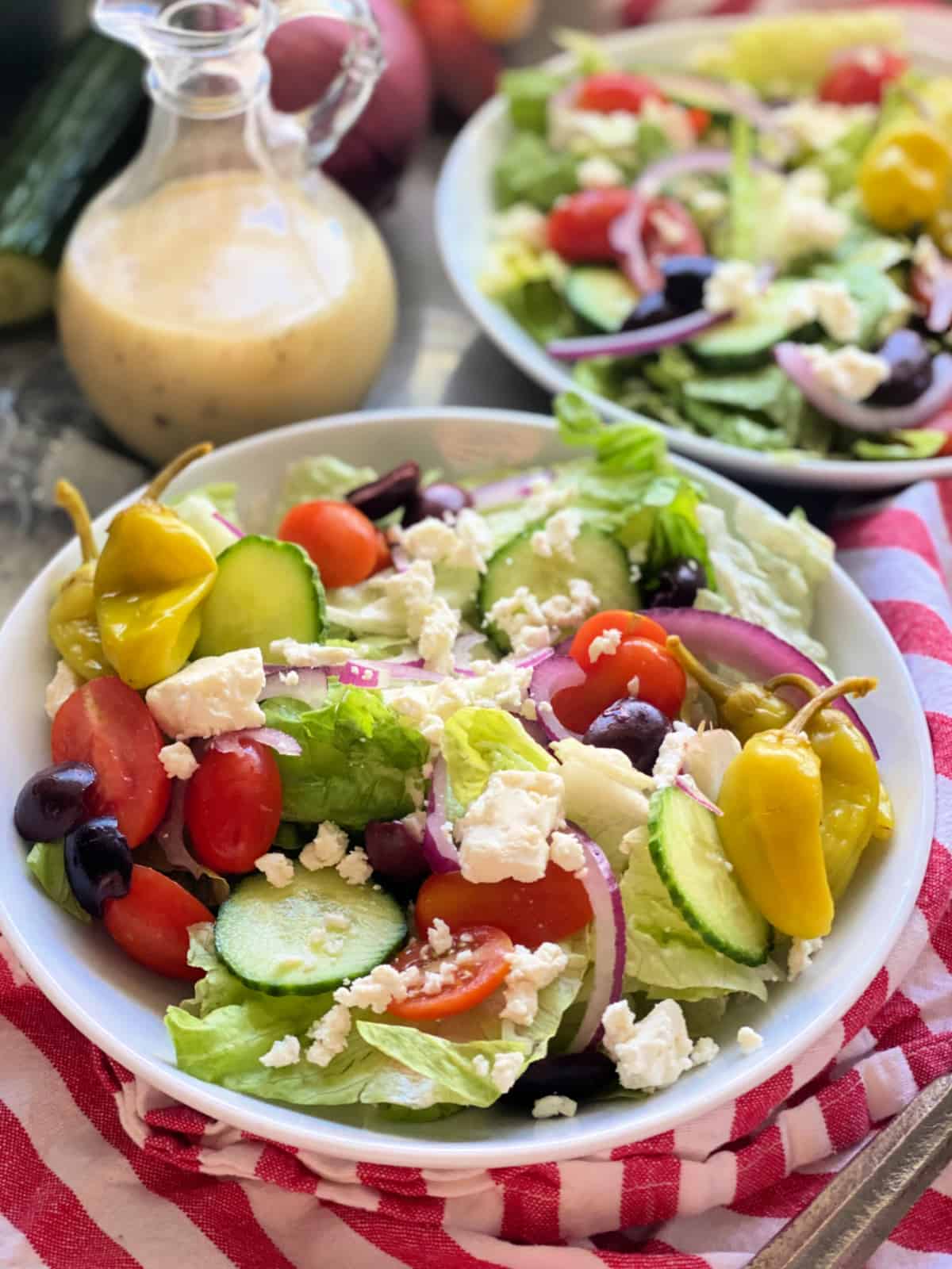 White bowls with salad with vegetables and feta in it.