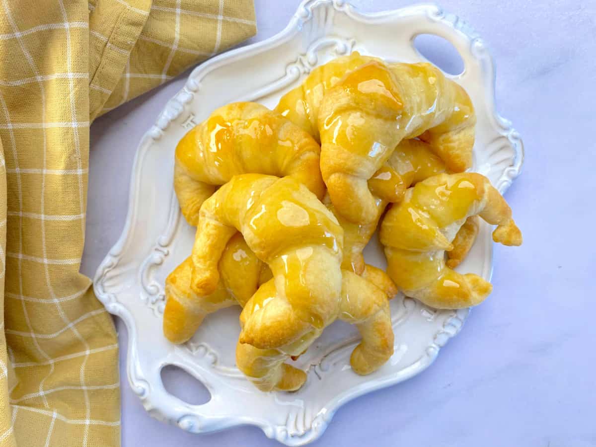 White oval platter with 8 croissants with honey butter poured on top.