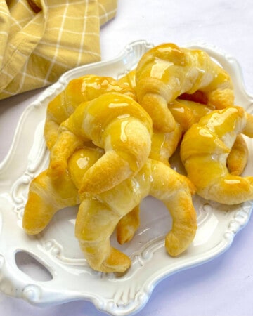 Square photo of an oval platter on a white countertop with baked croissants on top.