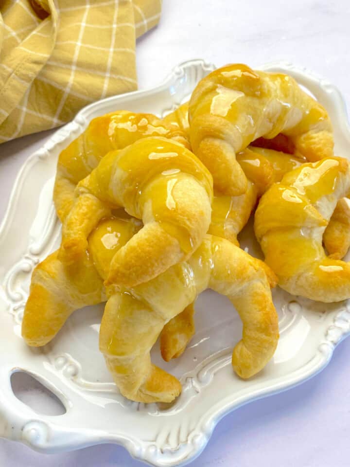 Square photo of an oval platter on a white countertop with baked croissants on top.