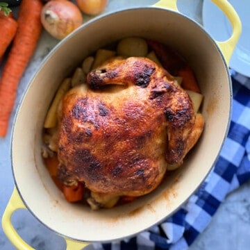 oval baking dish with a whole chicken and vegetables.