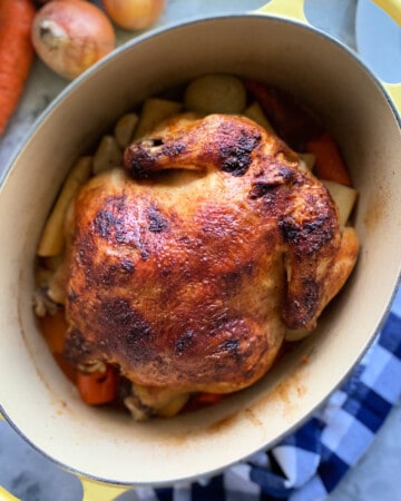oval baking dish with a whole chicken and vegetables.