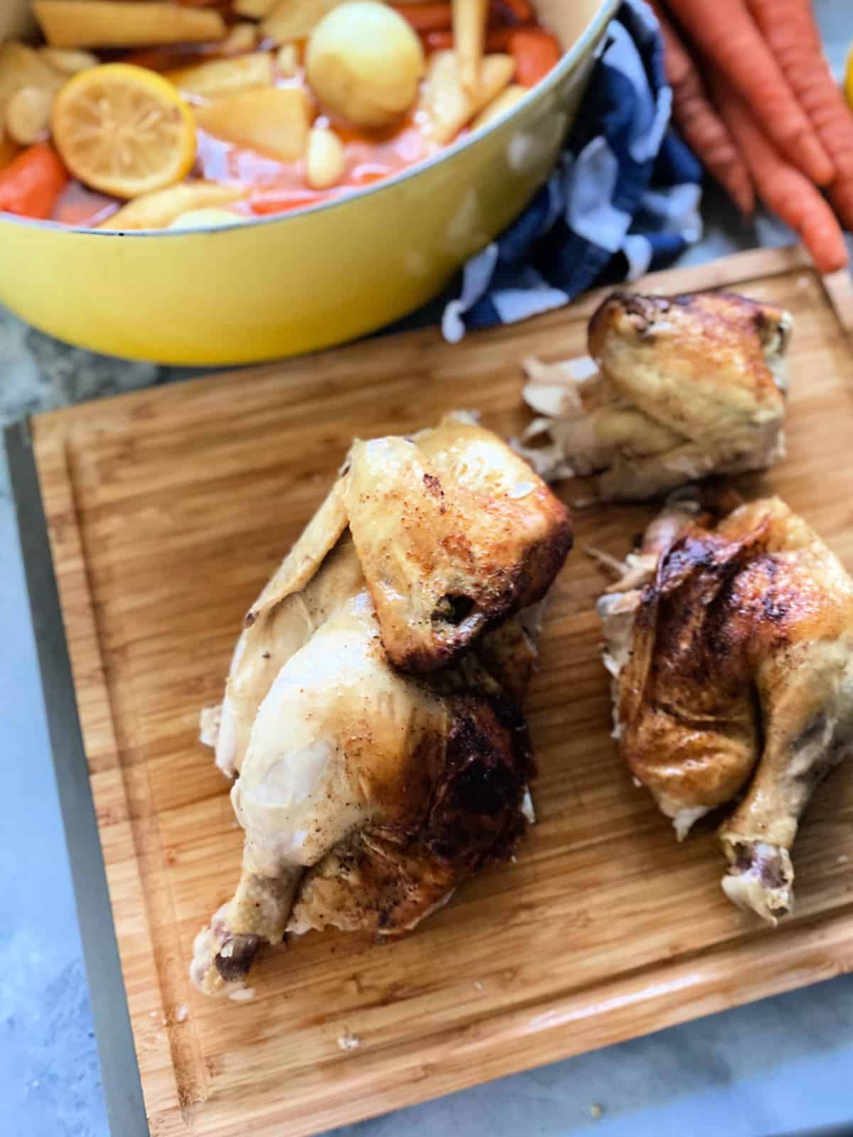 Wood cutting board with whole chicken cut into pieces.