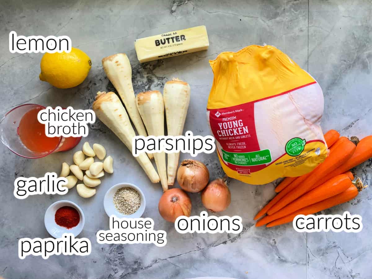 ingredients on counter: whole chicken, carrots, parsnips, onions, garlic, paprika, house seasoning, butter, and lemon.