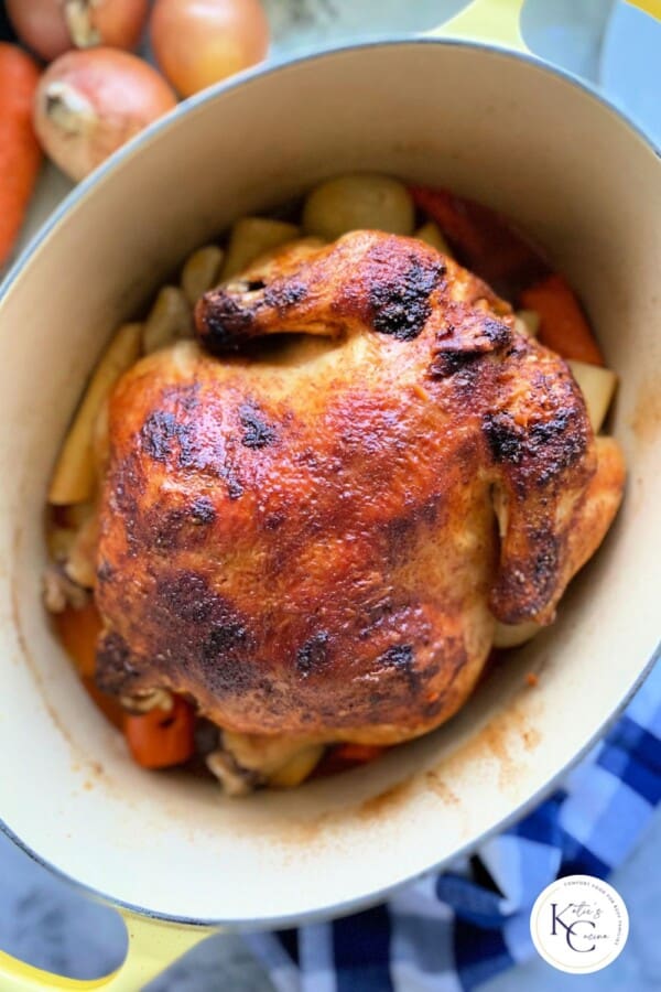 Seasoned brown chicken in an oval baking dish filled with veggies and logo on the right corner.