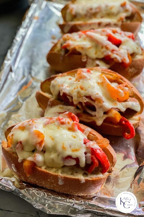 Sausage and Pepper Subs laying on an aluminum foil covered baking sheet.