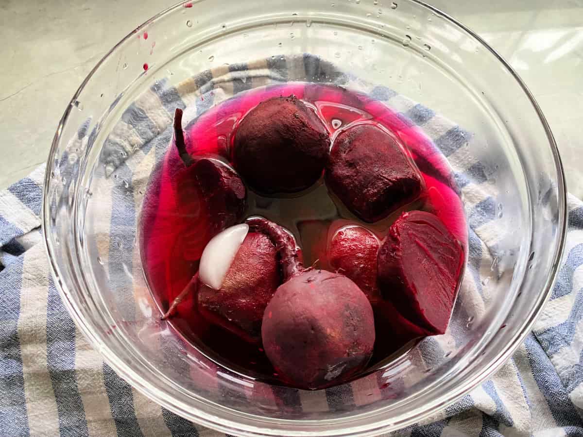 Glass bowl filled with beets soaked in water and ice.
