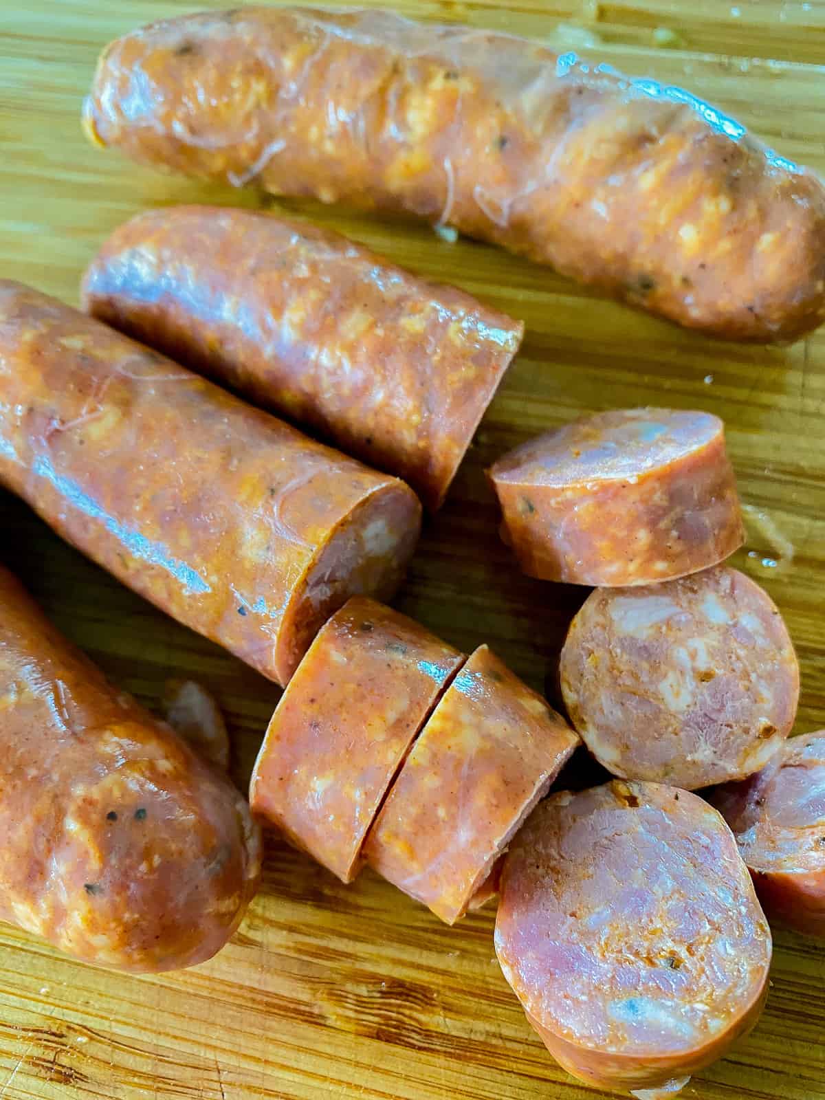 Sausage links with sliced sausage on a wood cutting board.