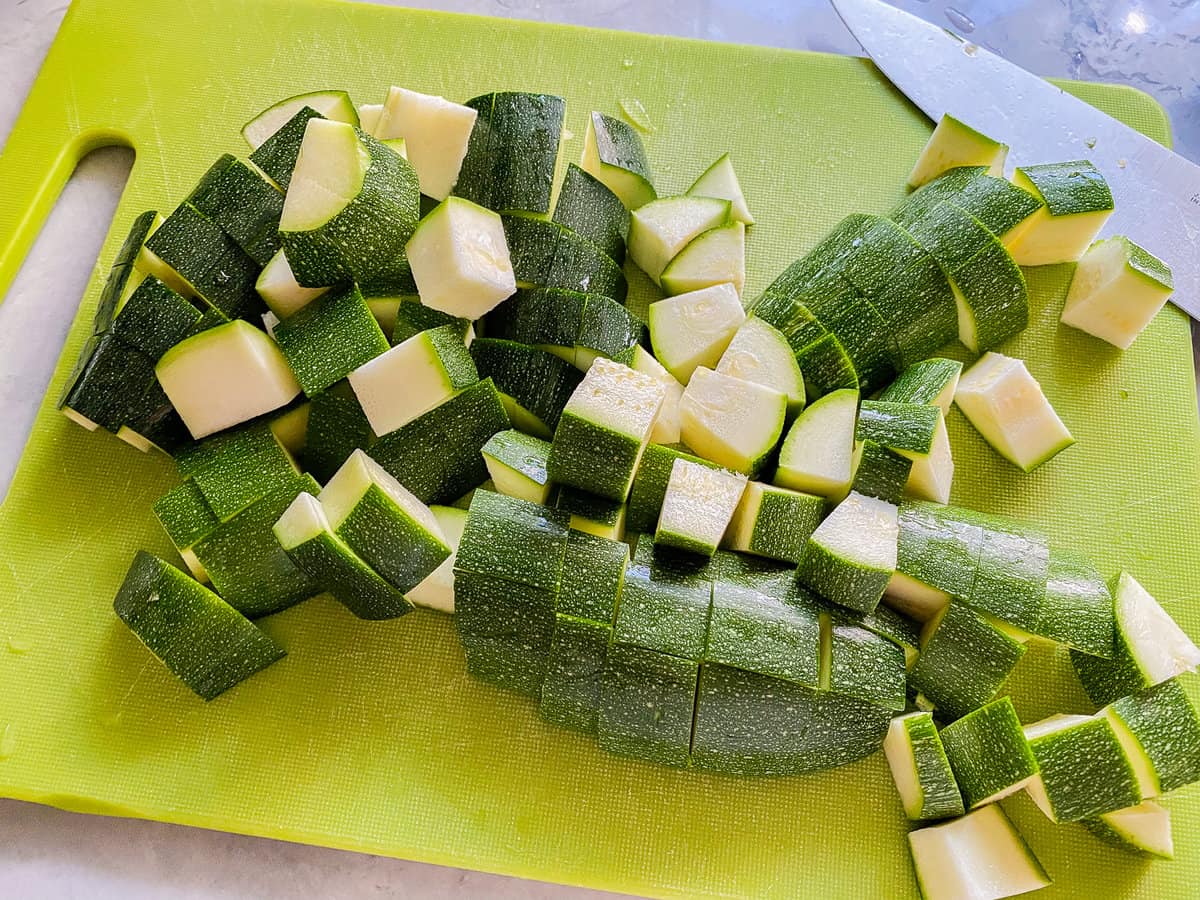 Diced zucchini laying on a cutting board.