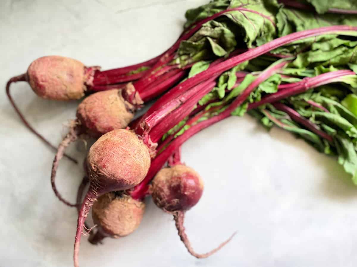 Fresh bundle of beets on a marble countertop.