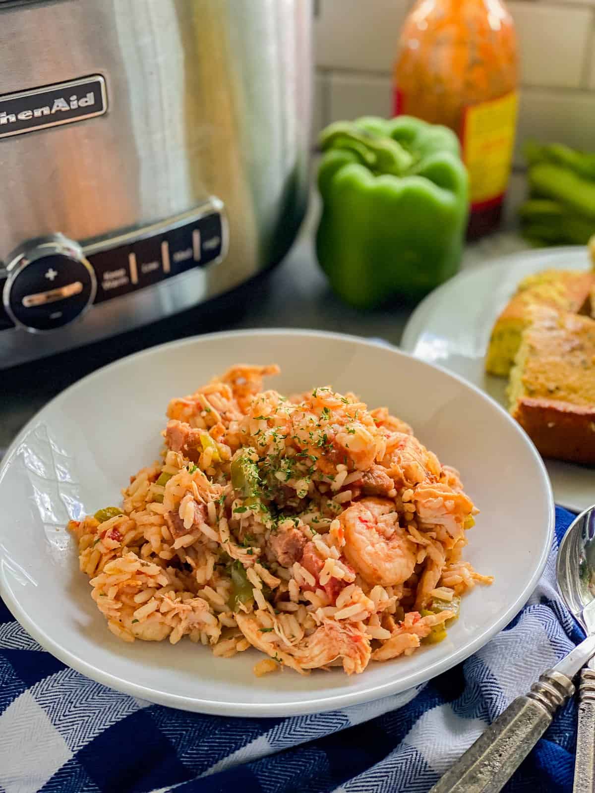 White circular bowl filled with shrimp, chicken, and rice with cornbread on the side.