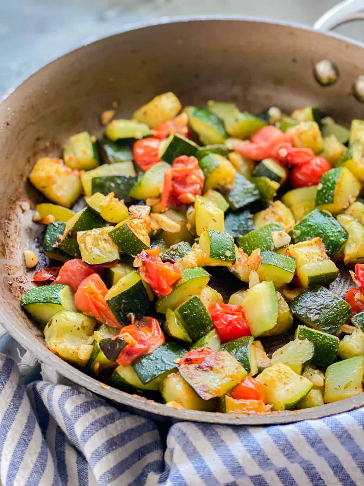 Sautéed zucchini and tomatoes resting in a pan.