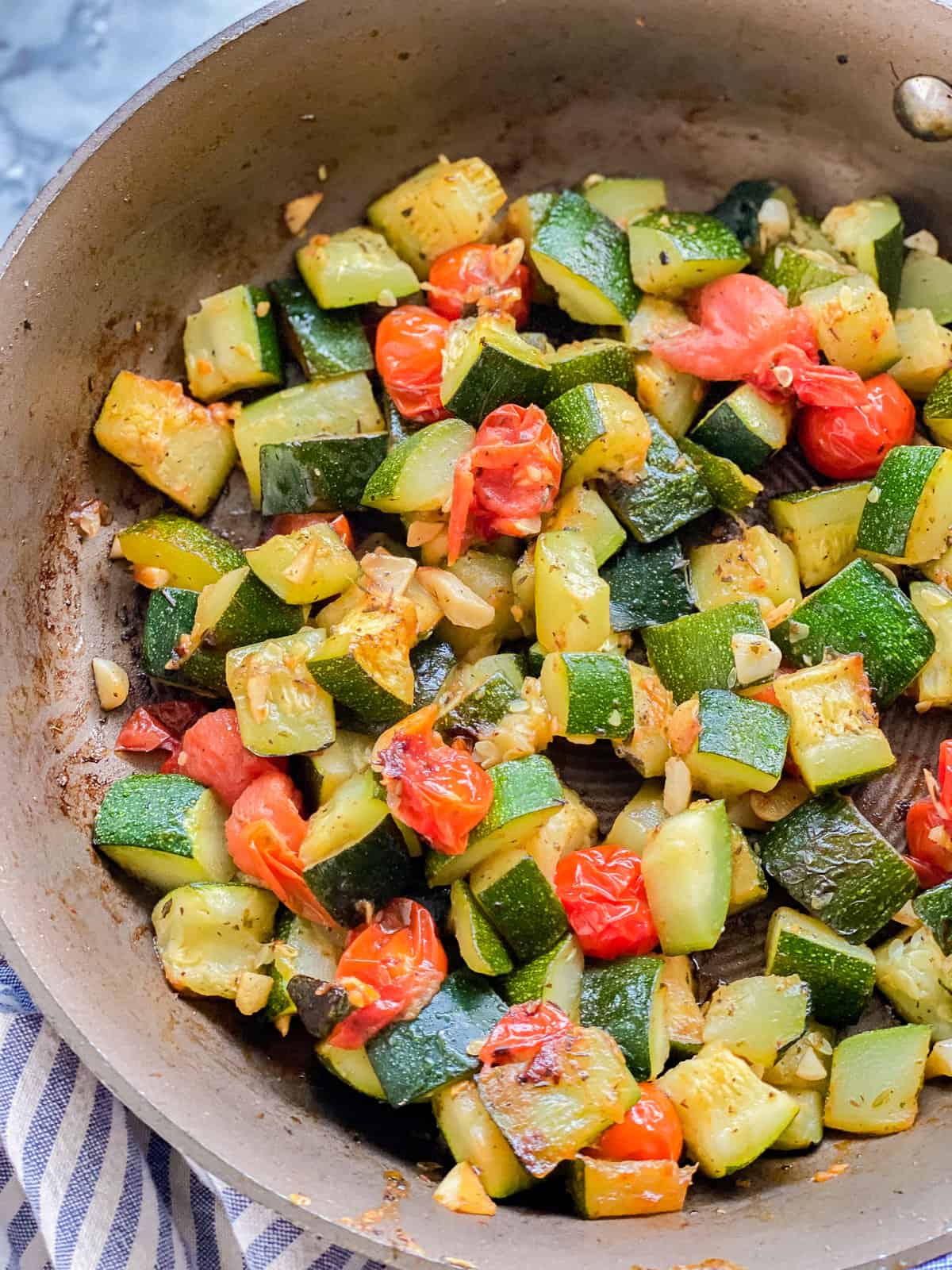 Sautéed zucchini and tomatoes resting in a pan.