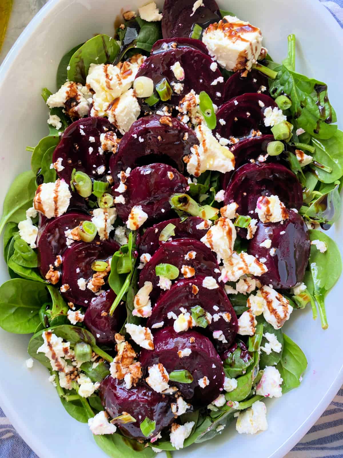 Spinach, beets, and feta in a white bowl.