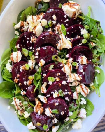 Spinach, beets, and feta in a white bowl.