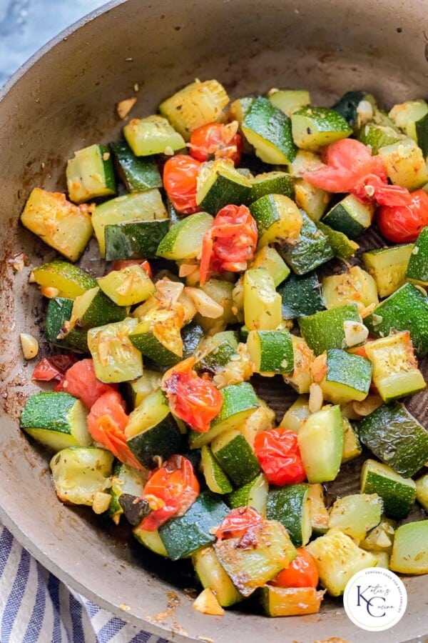 Sautéed zucchini and tomatoes on a pan.