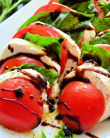 Slices of tomato, mozzarella and basil with balsamic drizzled on top.