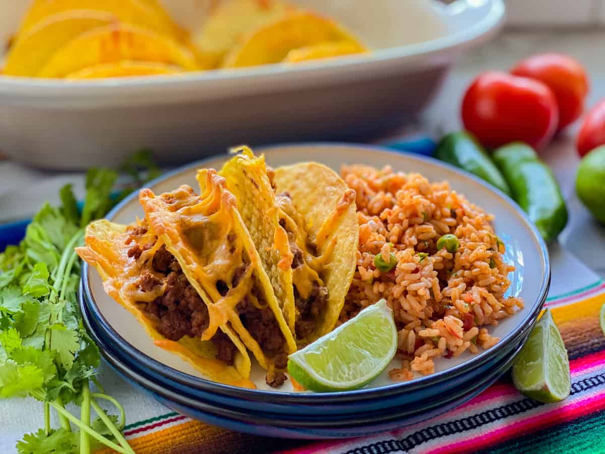 Front portrait of beef tacos served on a plate with a lime and rice.