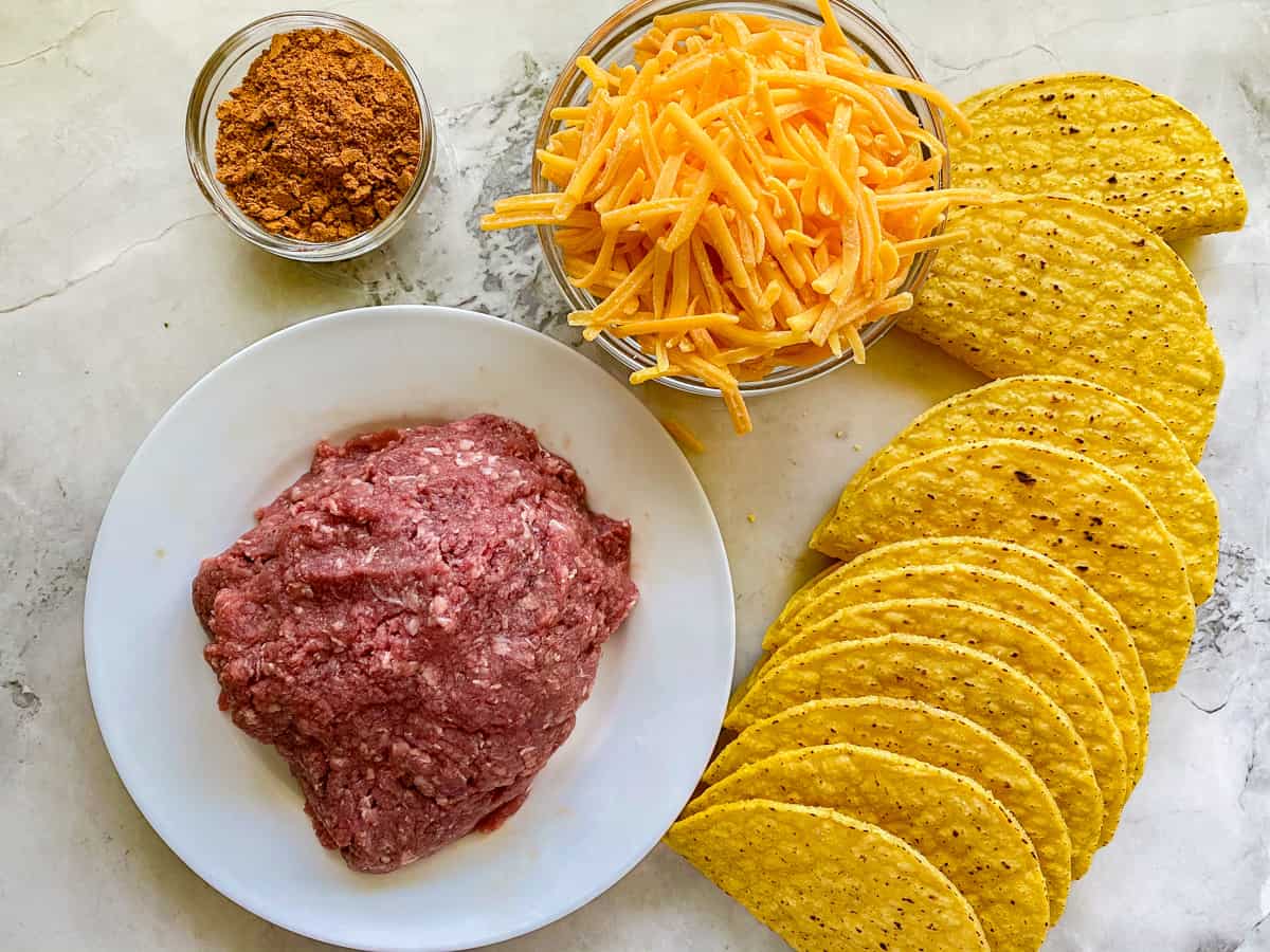 The ingredients for the beef taco recipe resting on a white marble countertop.