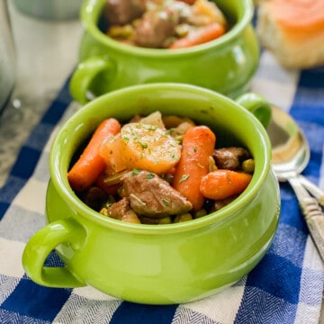 Close up of beef stew served in a mini green pot.